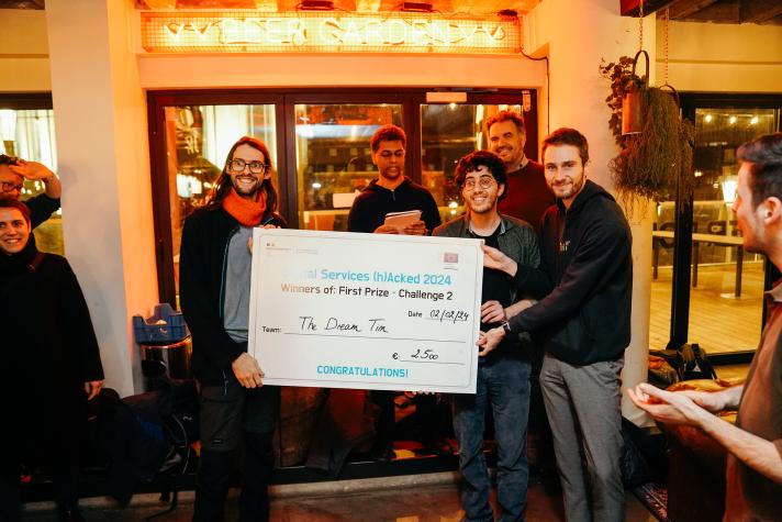 Hackathon winners pose with a big check