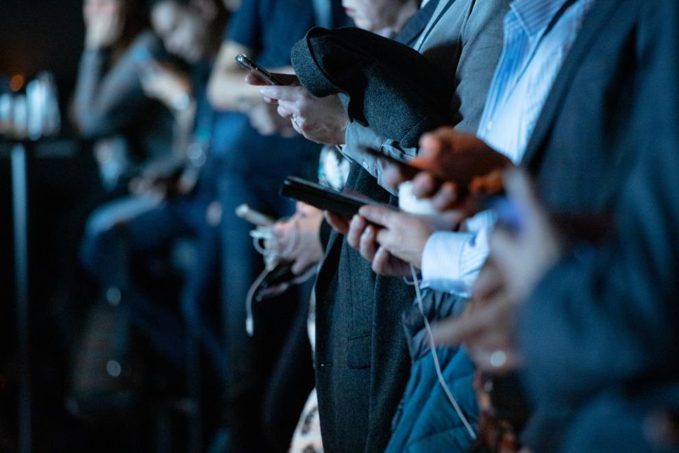 Row of people looking at their phones