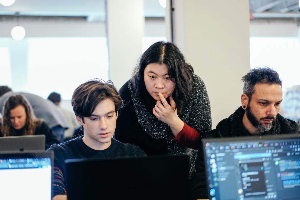 Three hackathon participants stare at their screens