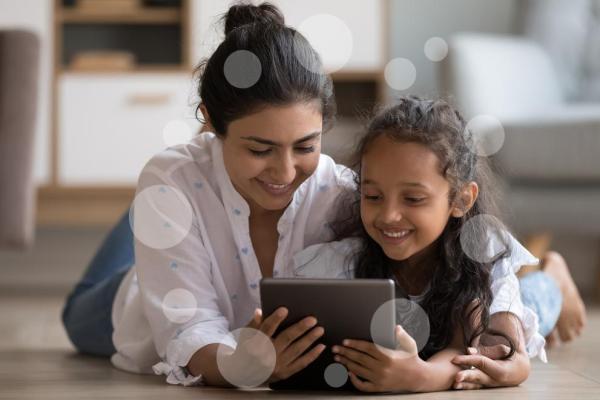 A woman and a kid watching a tablet and smiling